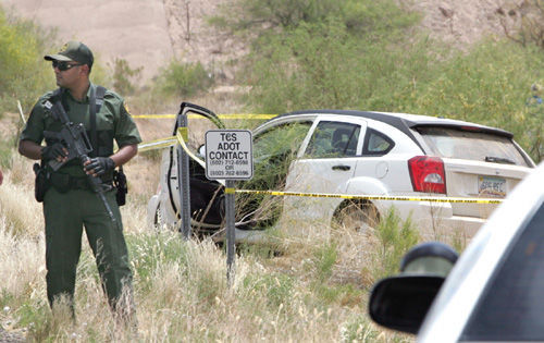 A U.S. Border Patrol agent stands next to a car that law enforcement officers pursued for 130 miles on Interstate 8 in southern Arizona. After the car was disabled, officers heard two shots. The bodies of Travis and Willard Twiggs were found in the car.